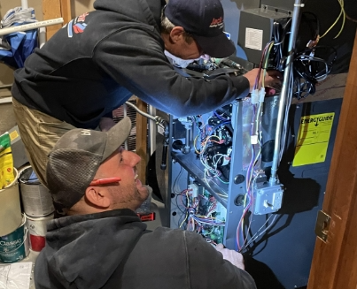 Two technicians working on a furnace.