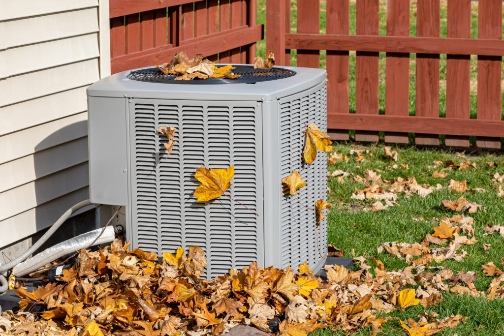 Outdoor HVAC system surrounded by fall leaves.